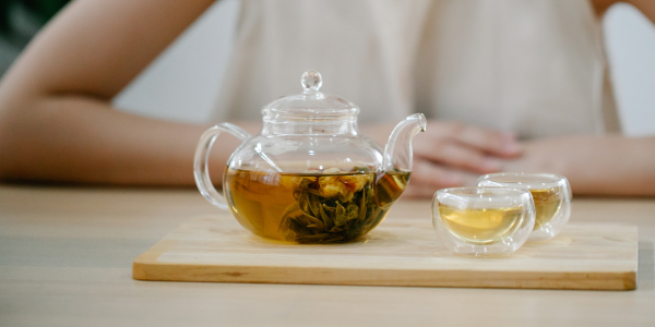 ガラスティーポットの茶葉が開くのを女性が待っている